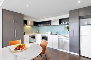 Une cuisine moderne avec des meubles gris, des plans de travail blancs et des appareils électroménagers en acier inoxydable.