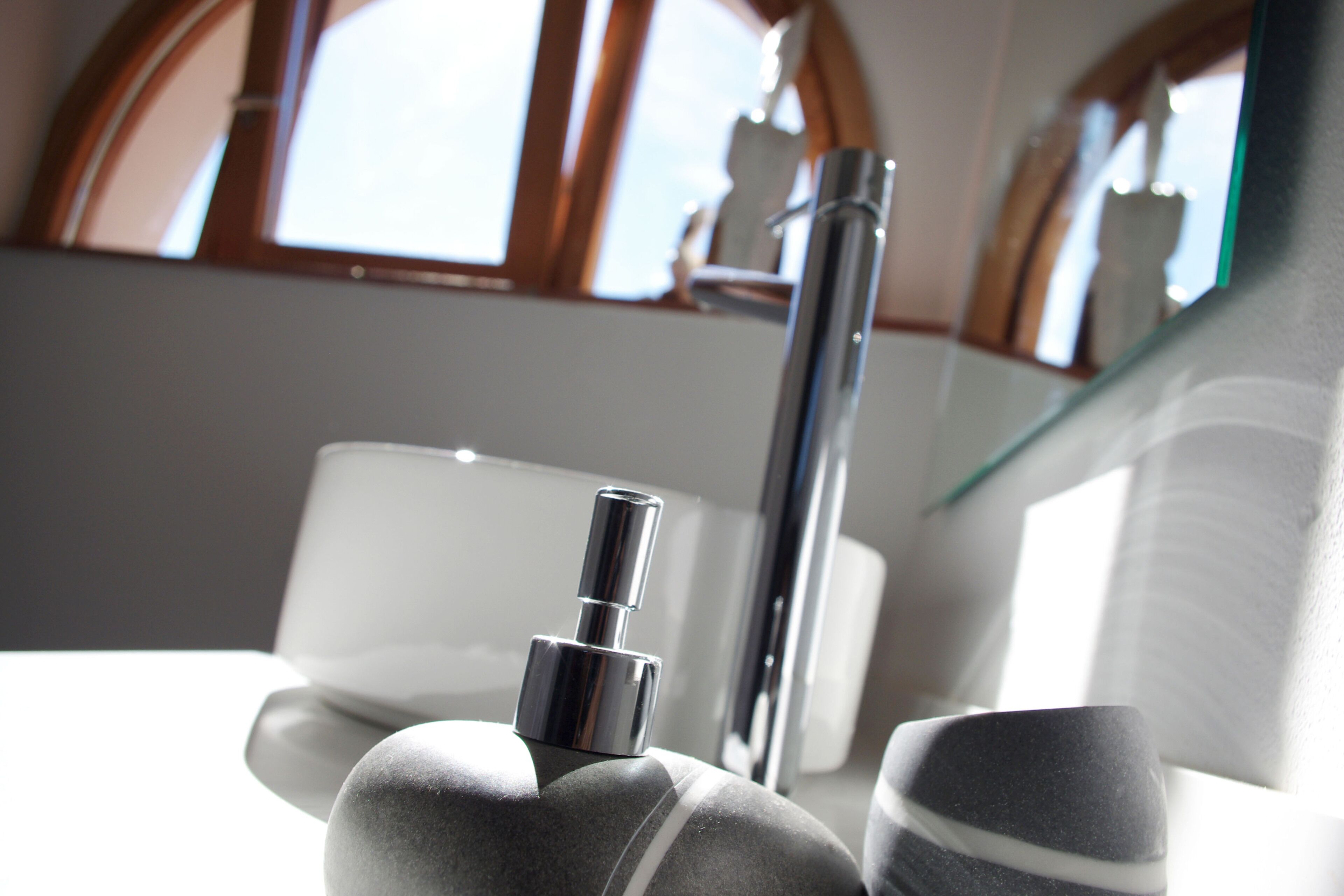 A bathroom with a modern design, featuring a chrome faucet, a white sink, and a glass shower enclosure.