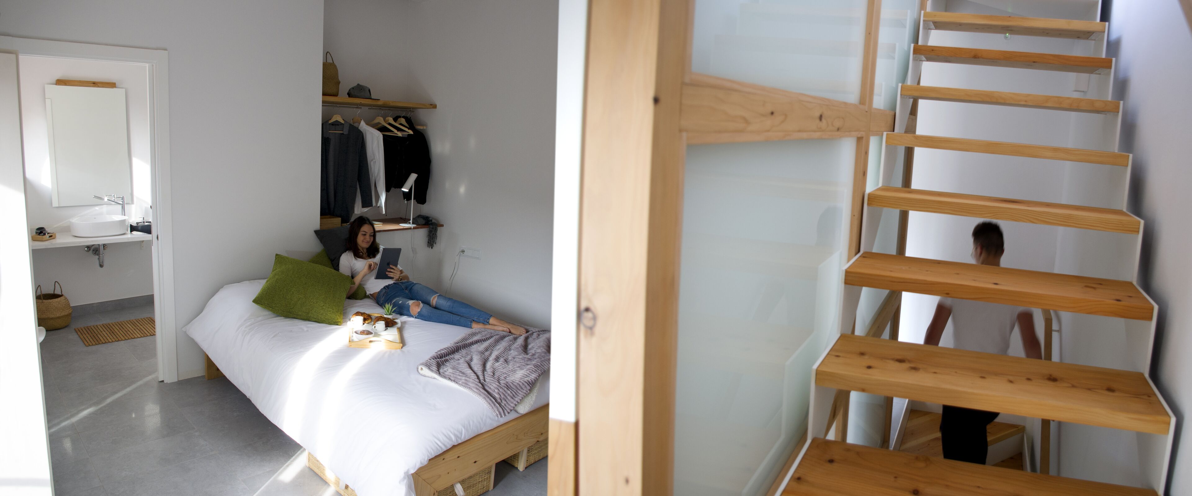 Un dormitorio con cama, mesita de noche, espejo, estante con ropa y una escalera de madera.