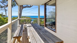 Terraza de madera con mesa y sillas, con vista al mar.