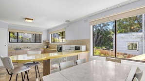 Una cocina moderna con una isla grande, taburetes de bar y una mesa de comedor.