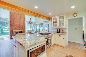 A spacious kitchen with a large island, wooden ceiling beams, and a brick wall. - Superb Park City Escape w/ Deck, Walk to Ski Lift! (Park City)