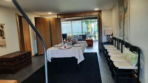 Un comedor con una mesa preparada para cuatro personas, un sofá y una fila de sillas.