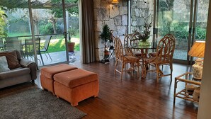 Una sala de estar acogedora con sofá, reposapiés y una mesa de comedor con sillas.