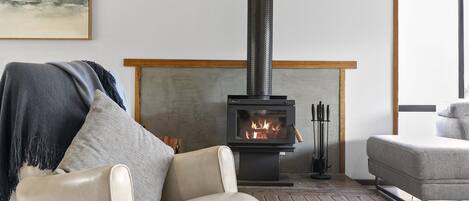 A modern living room with a wood-burning stove, leather armchairs, and a minimalist design.