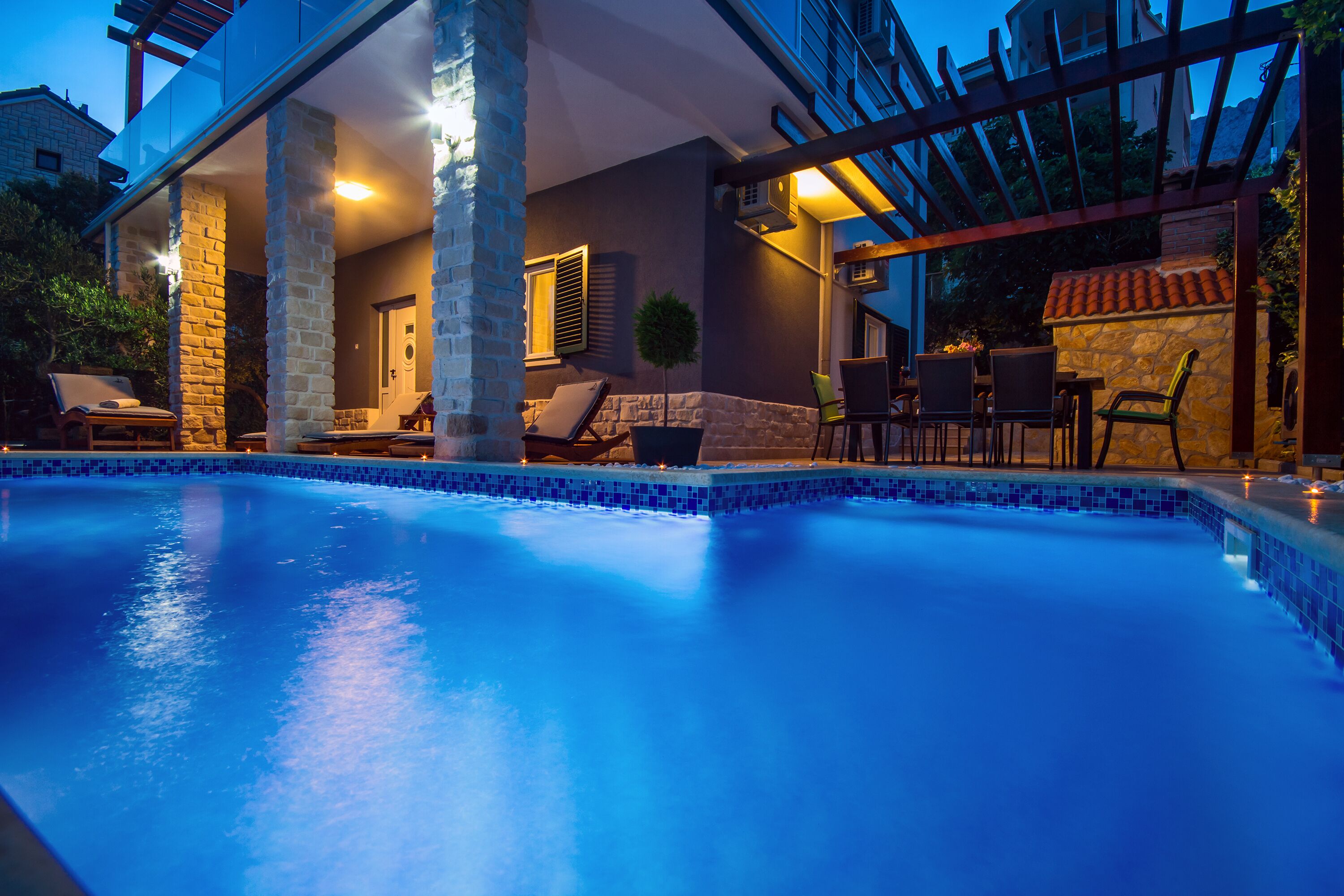En swimmingpool med solstolar och en pergola.