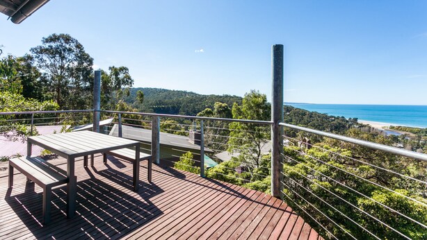 A wooden deck with a table and chairs, overlooking a coastal landscape with trees and a beach. - Seamist - Elevated With Amazing Outlook (Lorne)