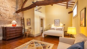 A cozy bedroom with a wooden dresser, a bed with patterned pillows, a chair, and a rug. - Casa Grande - Minho's Guest (Braga)