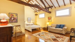 A cozy room with a bed, a sofa, a wooden floor, and a ceiling with exposed beams. - Casa Grande - Minho's Guest (Braga)