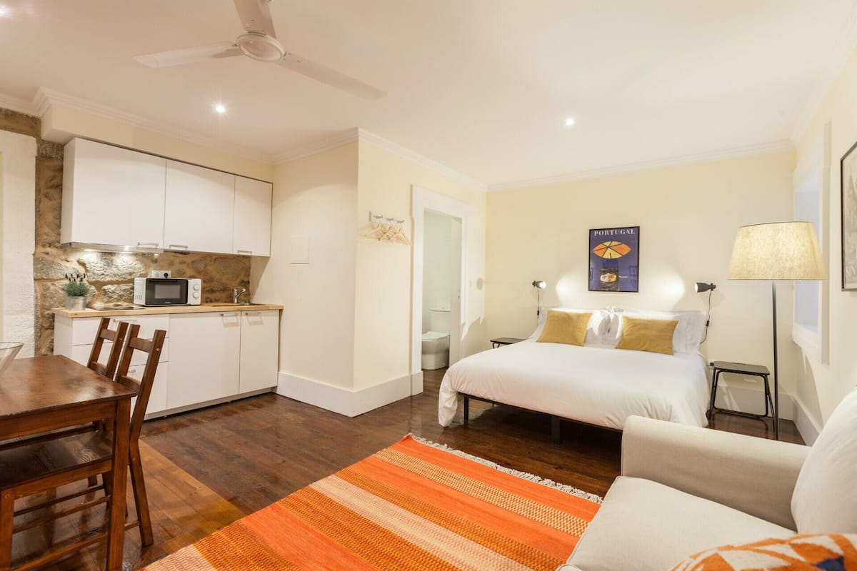 A compact hotel room with a bed, a desk, and a kitchenette.