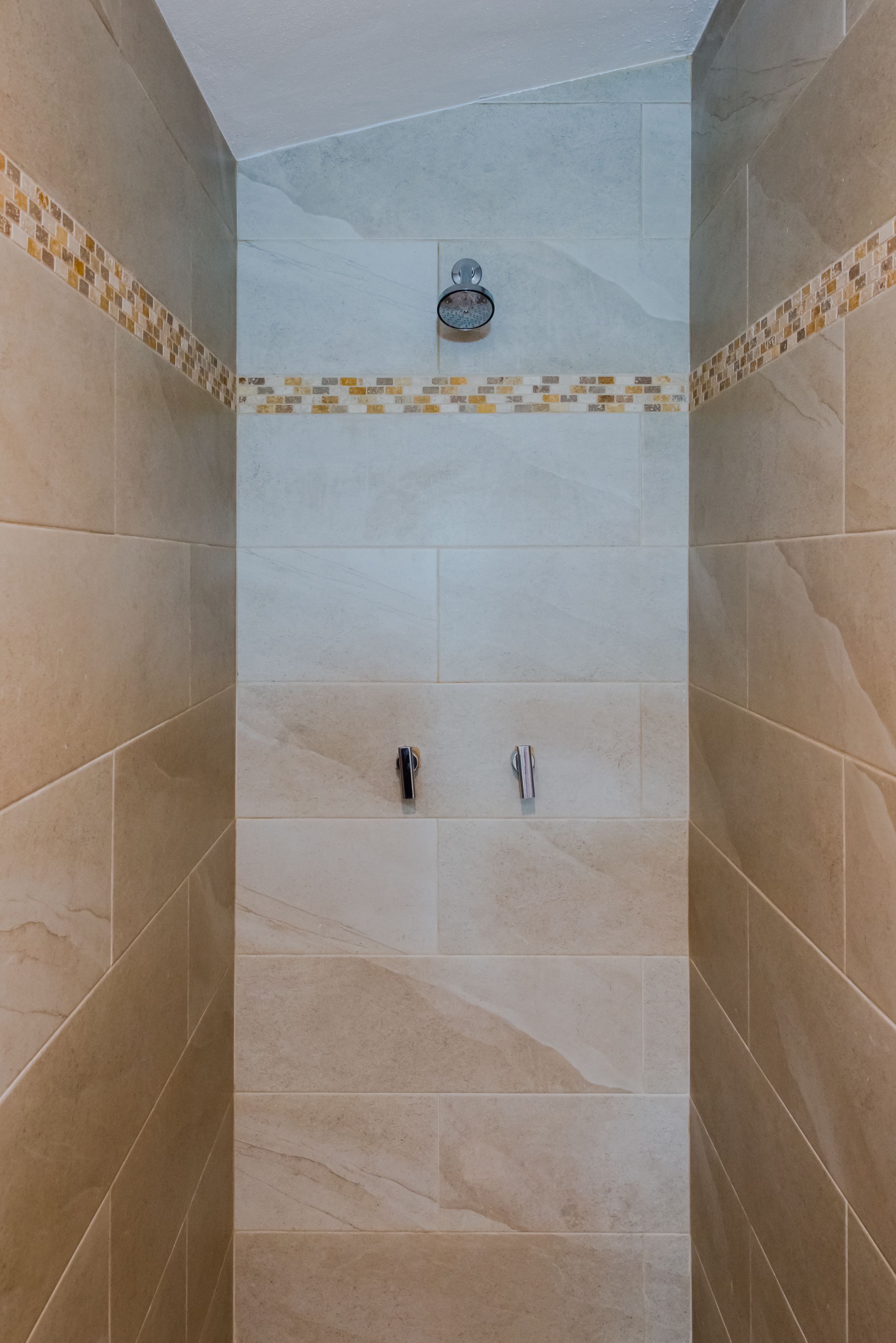 A shower area with beige tiles and a decorative border.