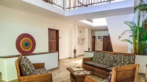 Een ruime woonkamer met een hoge plafond, houten meubels, een plafondventilator en uitzicht op het buiten.