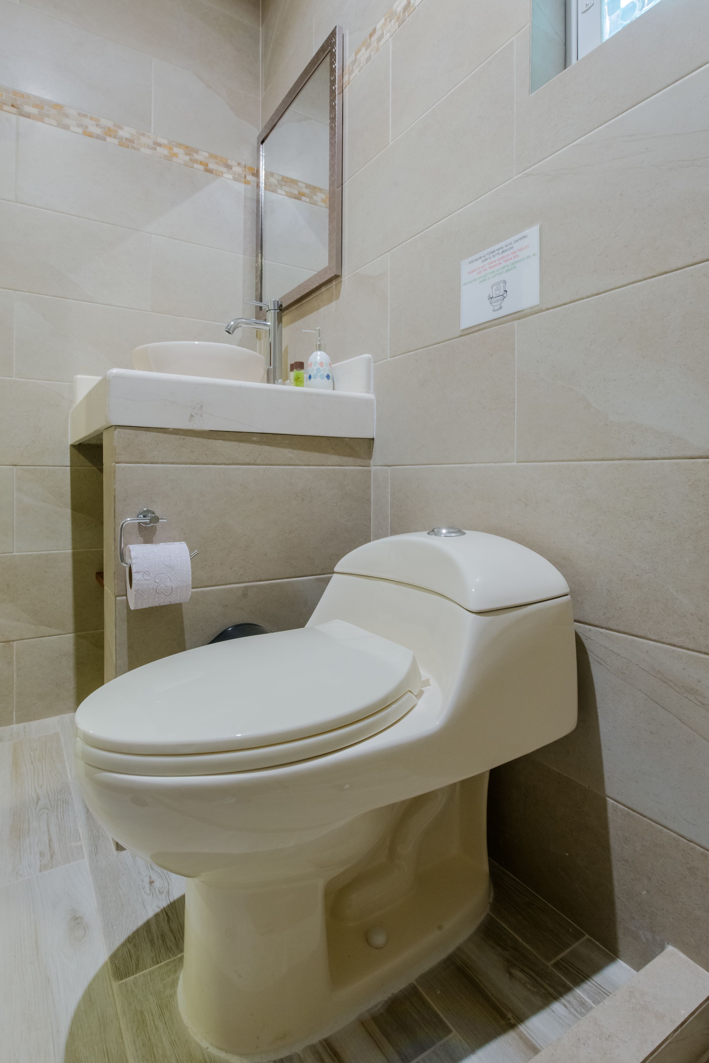 A bathroom with a toilet, sink, and mirror.