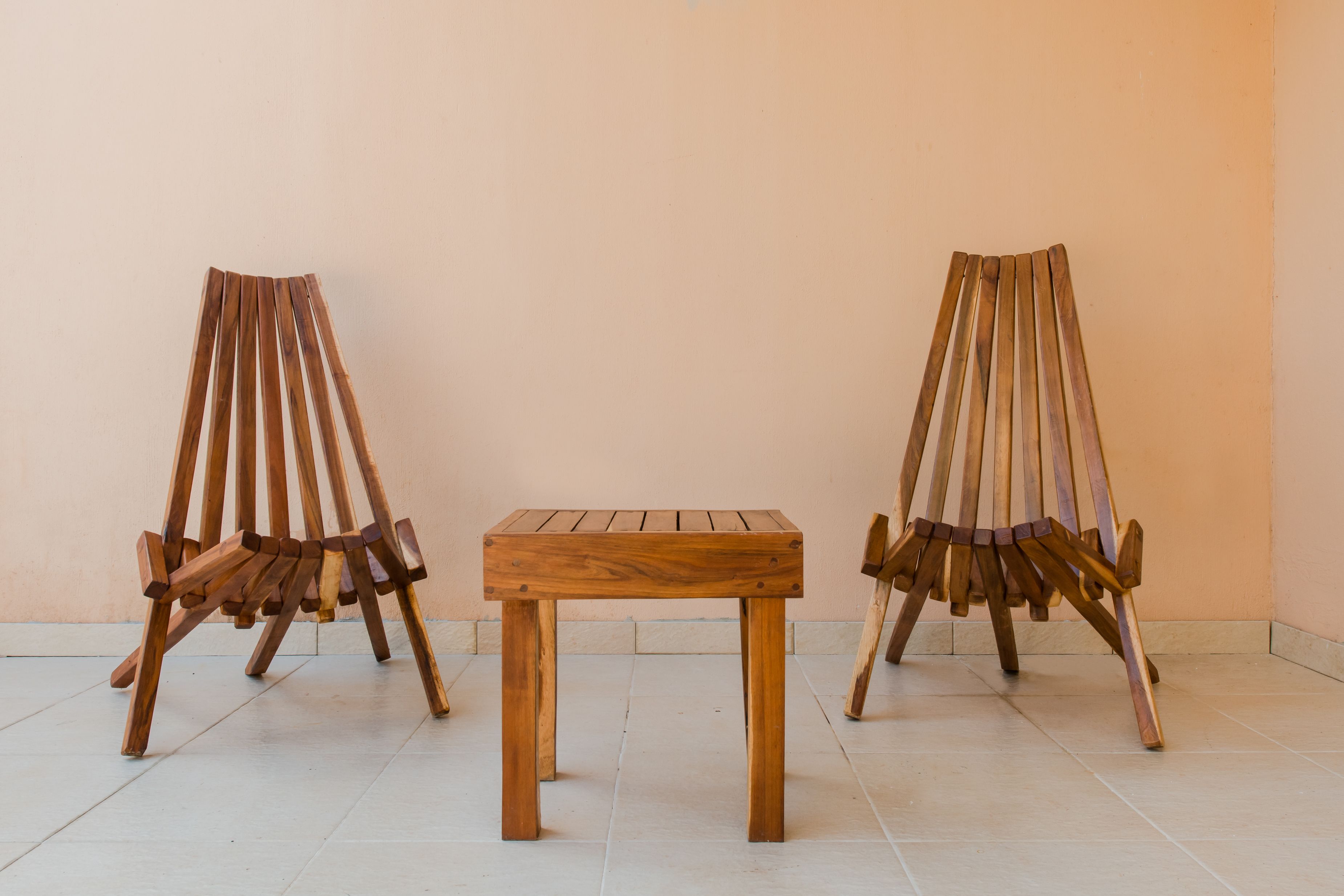 Two wooden easels and a small table in a room with plain walls and tiled floor.