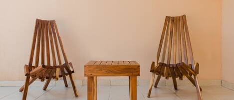 Two wooden easels and a small table in a room with plain walls and tiled floor.