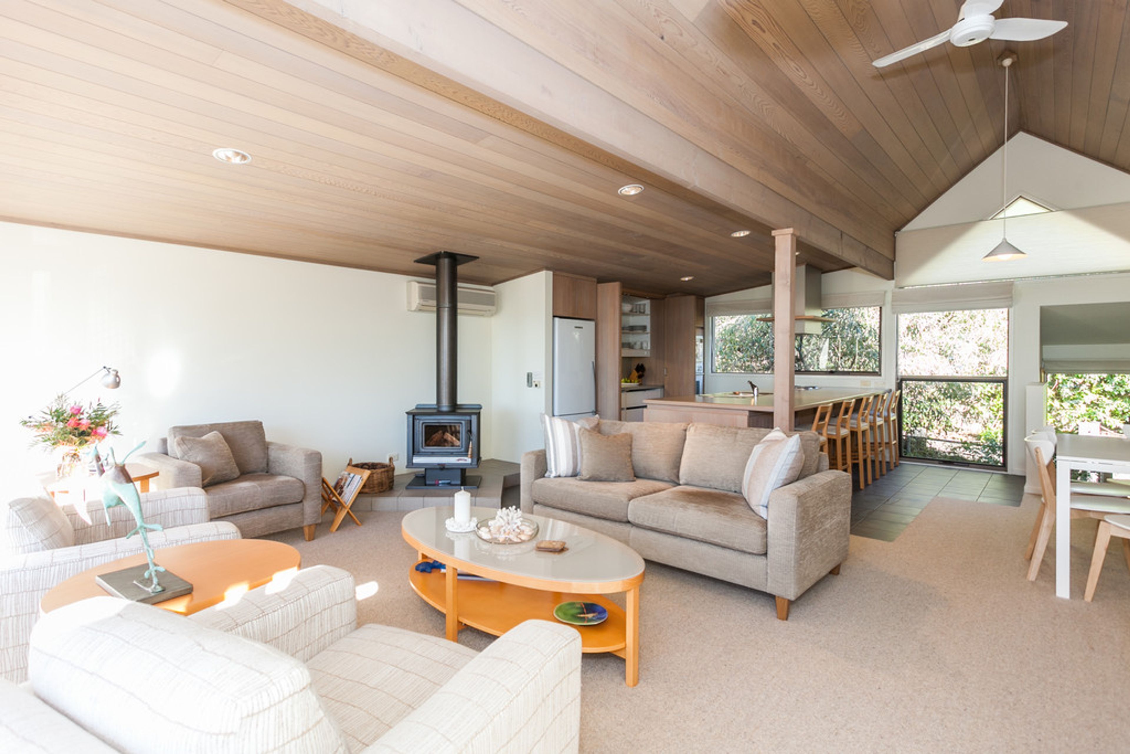 A spacious living area with a fireplace, sofas, and a dining area with natural light.