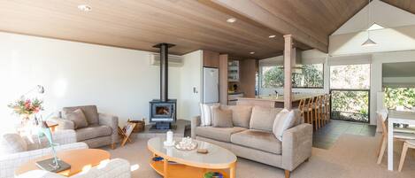 A spacious living area with a fireplace, sofas, and a dining area with natural light.
