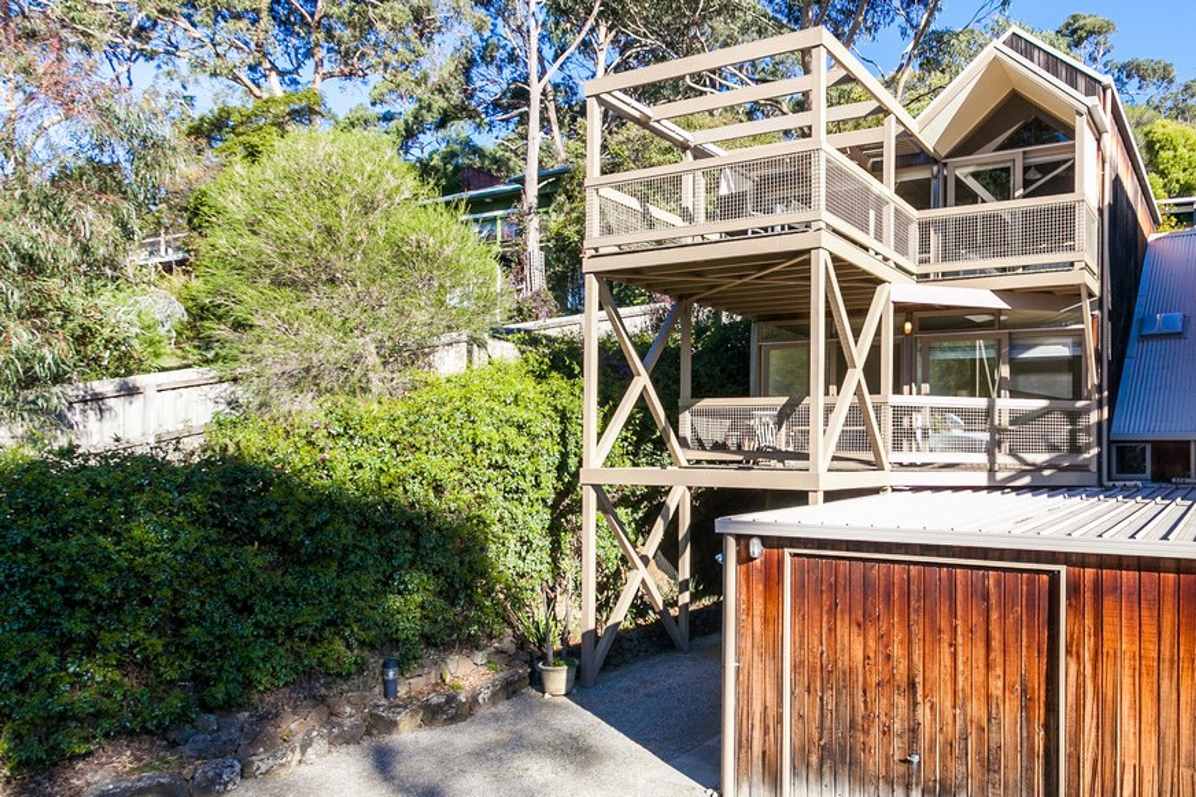 Eine mehrstöckige Holzkonstruktion mit Balkon, umgeben von viel Grün und Bäumen.