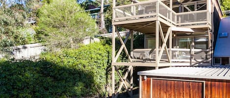 Eine mehrstöckige Holzkonstruktion mit Balkon, umgeben von viel Grün und Bäumen.