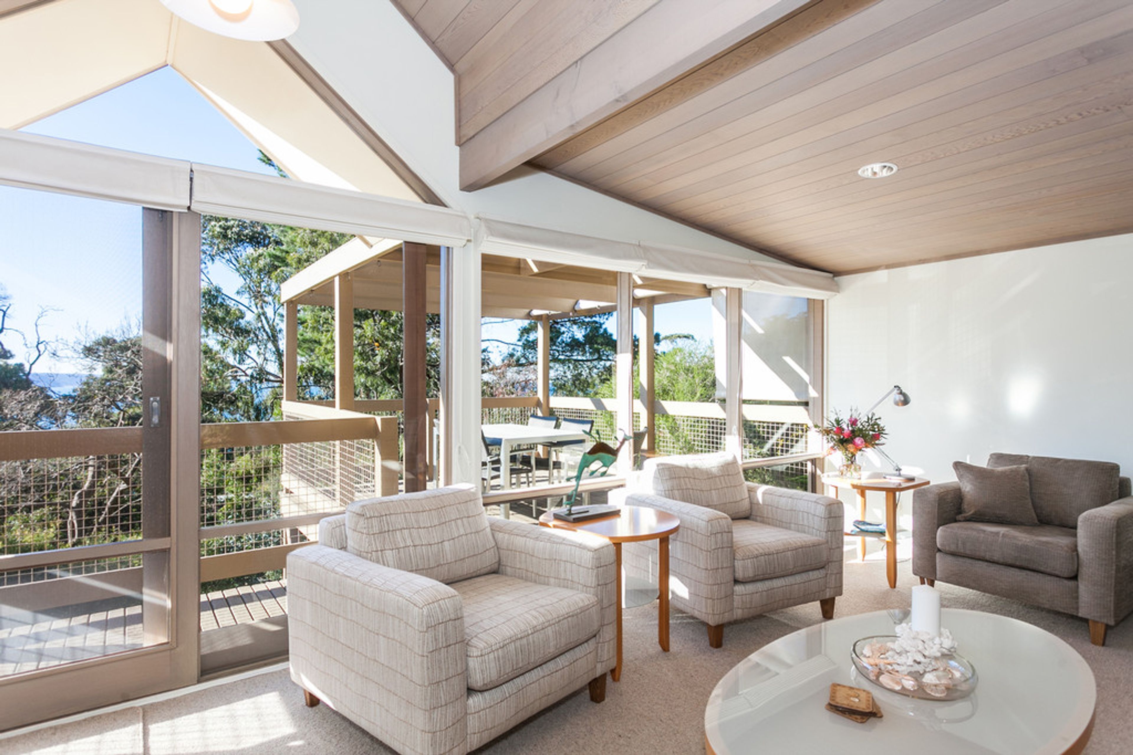 A spacious living area with a large glass door leading to an outdoor deck, furnished with sofas and a coffee table.