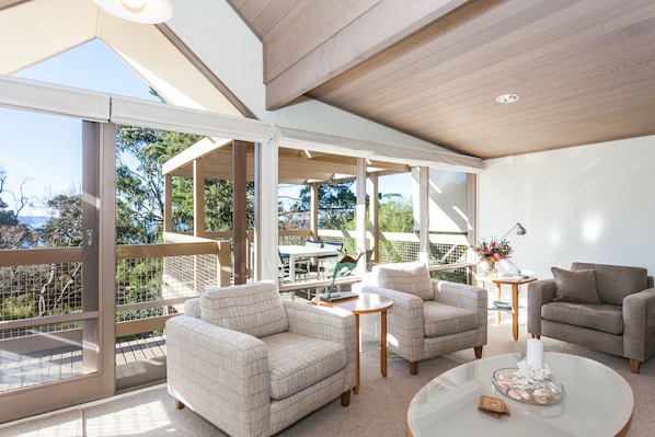 A spacious living area with a large glass door leading to an outdoor deck, furnished with sofas and a coffee table.