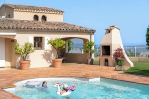 Un espace piscine doté d’une terrasse carrelée, d’une pergola et offrant une vue sur l’océan.