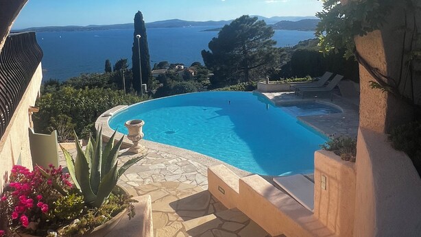 Ein Poolbereich mit freiem Blick auf das Meer und die entfernten Hügel.