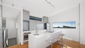 A modern kitchen with a central island, stainless steel appliances, and a large window providing a view.