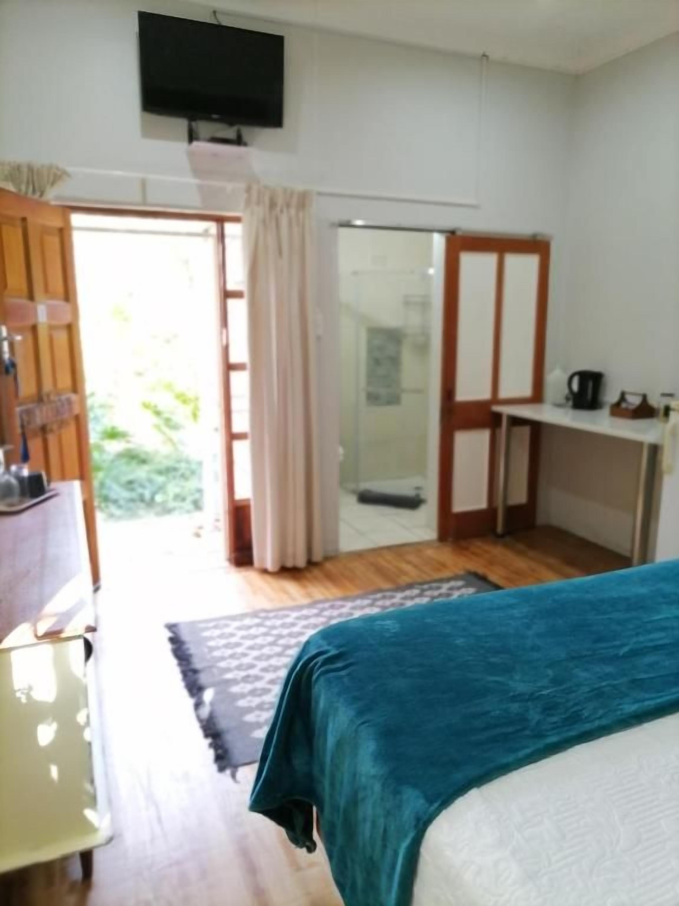 A room with a bed, a desk, a television, and a shower area.