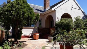 A building with a stone pathway leading to an entrance, surrounded by greenery and potted plants.