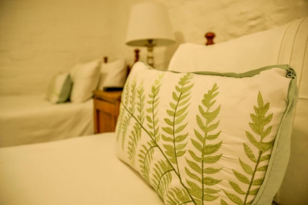 Una cama con un almohadón estampado con hojas.
