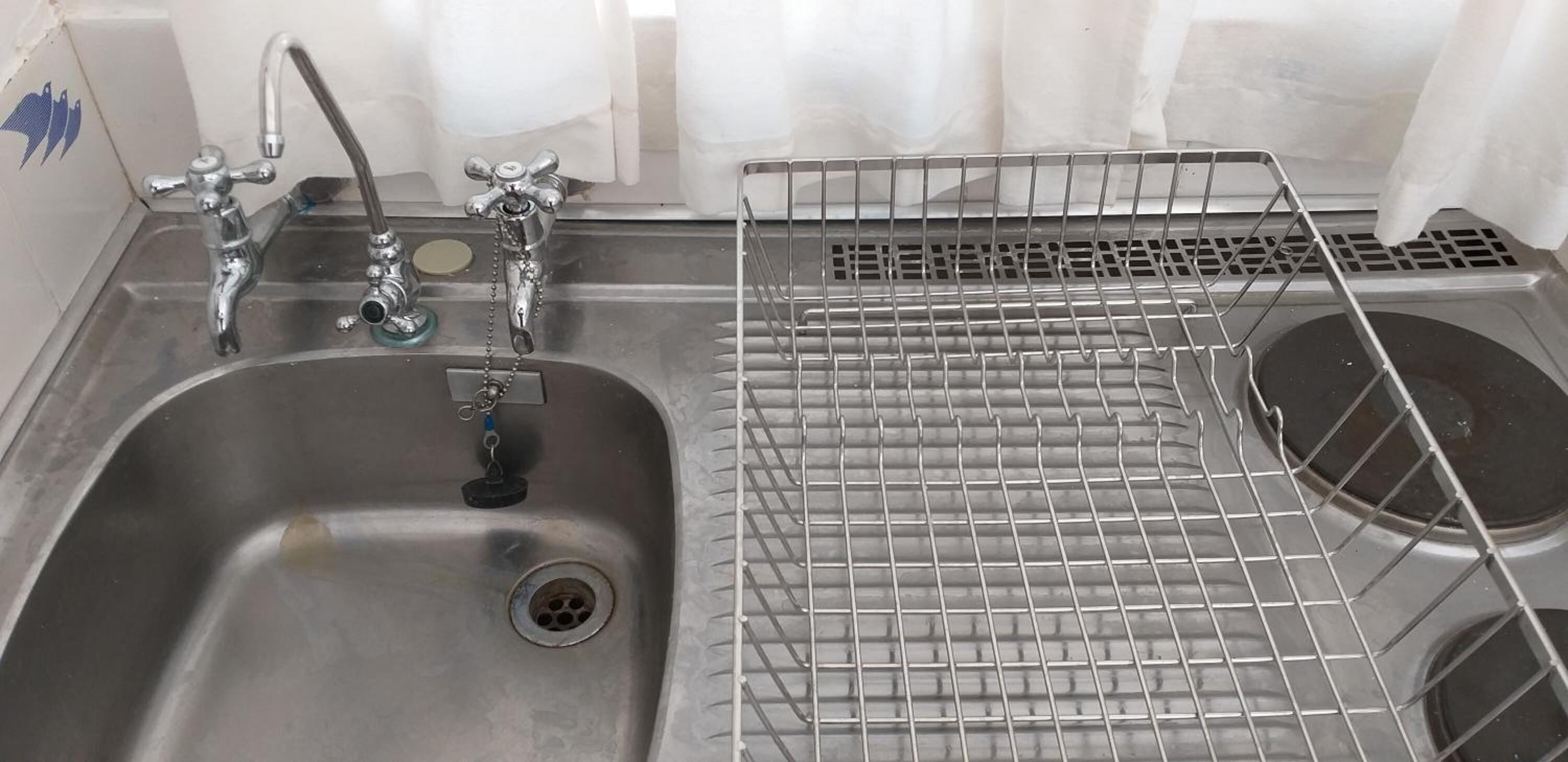 A stainless steel sink with two faucets and a drain.