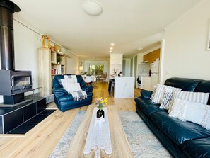 A modern living room with a fireplace, leather sofas, a coffee table, and a kitchen in the background.
