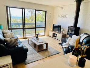 A modern living room with a large window, a fireplace, and a television. - Bayview Number Four (Lorne)