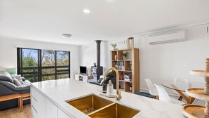 Uma cozinha moderna com ilha central, armários brancos e pia embutida.
