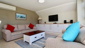 A living room with a sofa, coffee table, and a TV mounted on the wall.