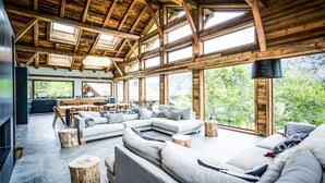 A spacious living area with a large sectional sofa, a dining table with chairs, and a kitchen in the background.