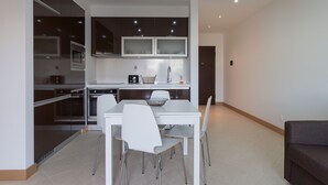 A modern kitchen with white cabinetry, a dining table with chairs, and a built-in oven. - Harris Apartment, Pool, Wifi (Lagos)