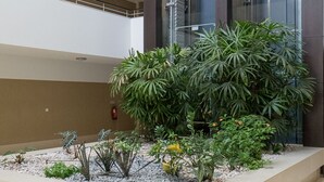A multi-level building with a central atrium featuring a landscaped garden with various plants and a fire extinguisher on the wall. - Harris Apartment, Pool, Wifi (Lagos)