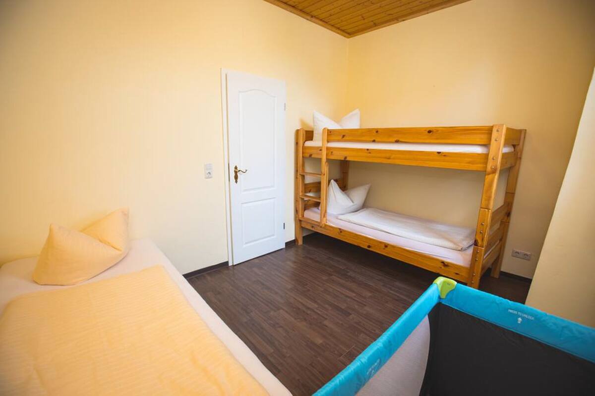 Una habitación con literas, una cama individual, una puerta y una ventana.