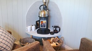 A cozy room with a wood-burning stove, a coffee pot, and a basket of firewood.