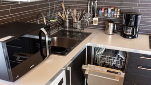 Una cocina moderna con lavadora y secadora integradas, electrodomésticos de acero inoxidable y salpicadero de azulejos.
