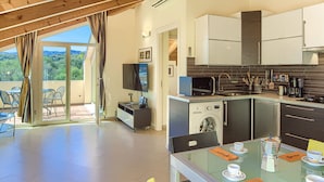 Una cocina moderna con lavadora integrada, un comedor con mesa de vidrio y vistas al exterior.
