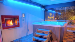 Un baño moderno con bañera de madera, chimenea y ventana con vista a la ciudad.