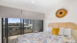 A bedroom with a large bed, a balcony, and a view of the outside.