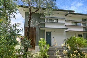 A modern two-story building with a flat roof, a front door, and a staircase leading to the entrance. - Sandy Beach Apt 6 (Lorne)