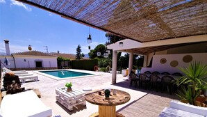 Un espace aménagé au bord de la piscine, avec une table en bois, des chaises longues et un coin repas.