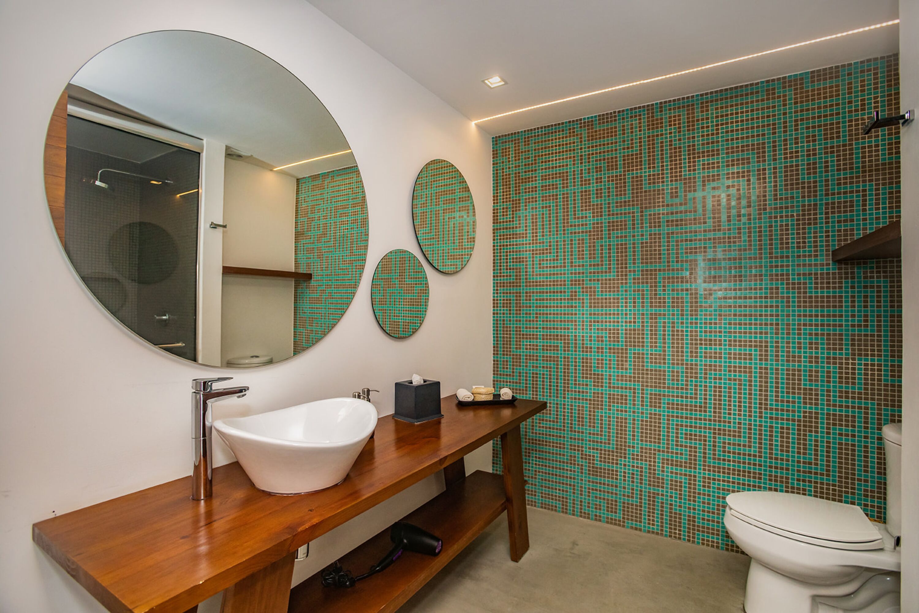 A modern bathroom with a wooden vanity, a white sink, and a large mirror.