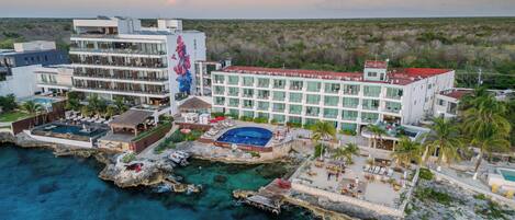 A hotel with multiple floors, a pool, and a view of the ocean.
