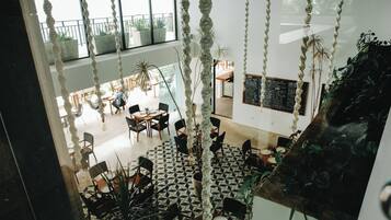 A spacious indoor area with high ceilings, geometric patterned flooring, and hanging rope decorations.